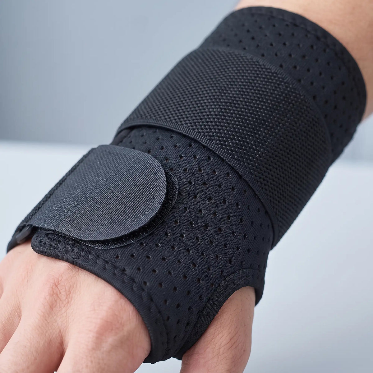 Detail zapínání bandáže ErgoWrist — široký pružný pás a kulatá patka na suchý zip